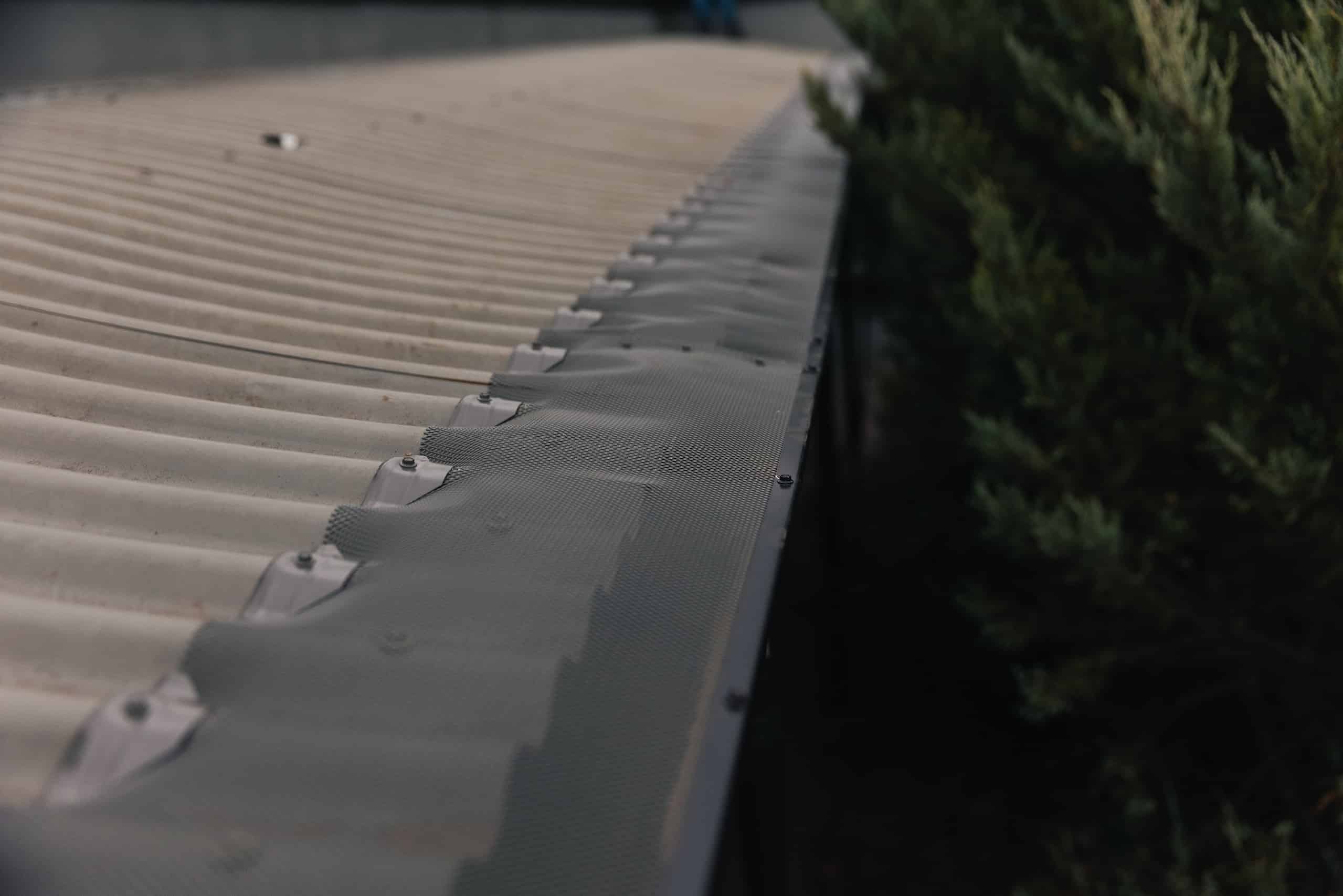 Powder-coated aluminium gutter guard blending with a residential roof, offering durable protection against birds and reducing gutter maintenance.